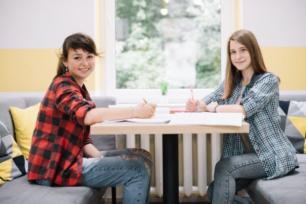 two smiling girls desk with textbooks